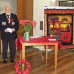 A resident with medals stands to give a speech for Anzac day