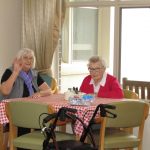 Two residents wave from their lunch table