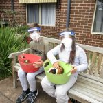Two children in face masks pat guinnea pigs in baskets