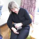 A resident holds a bunny in her lap while sitting down