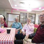 Residents smiling around a chequered table with decorations on the ceiling