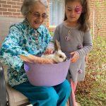 A female resident and young child look at a bunny in a basket