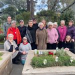 Residents smiling around a thriving communal herb garden