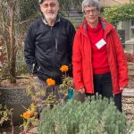 Residents smiling around a thriving communal herb garden