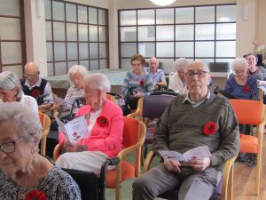 Residents sit and read the printed materials for an Anzac Day Service